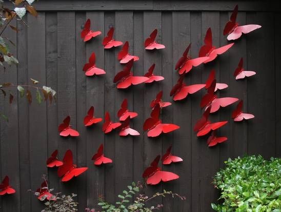 A black fence with 3d red butterflies